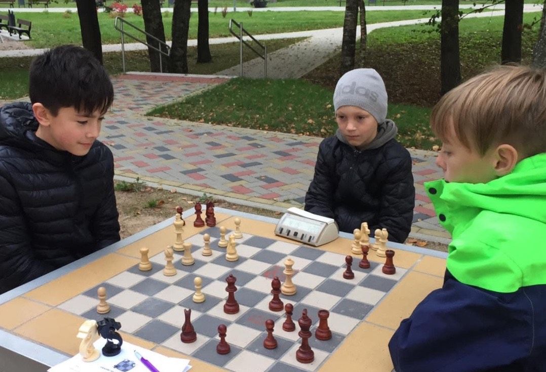 Ратмир, Эмиль и Эдгарас играют в шахматы на детской площадке