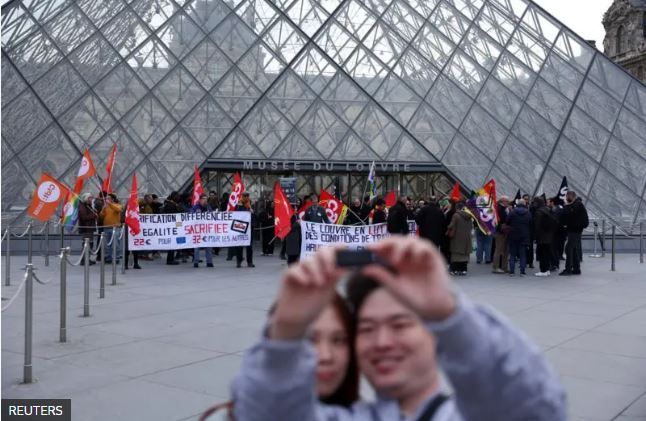 Туристы делают селфи на фоне очереди в Лувр, который не открылся по расписанию 17 декабря