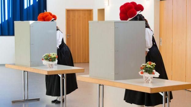 AFP Image caption Эти женщины пришли на избирательный участок в традиционных для Шварцвальда красных шляпах "болленхут"