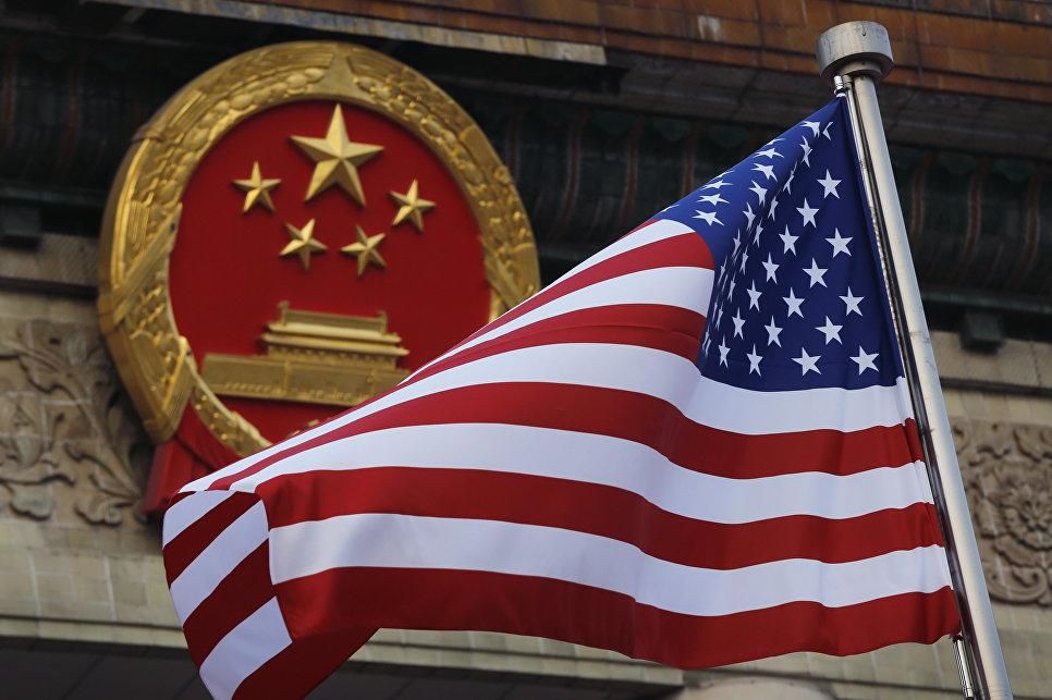 © AP Photo / Andy Wong, File Флаг США на фоне эмблемы Китая в Пекине