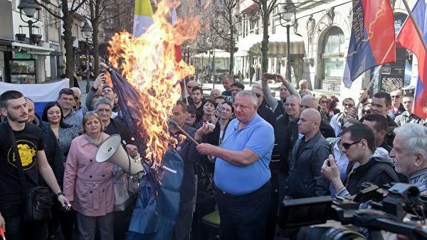 © AP Photo / Marko Drobnjakovic Воислав Сесель, лидер ультранационалистической сербской радикальной партии, держит горящий флаг НАТО на акции протеста в Белграде, Сербия. 24 марта 2019