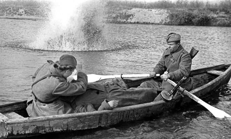Санинструктор сержант В. Росликова в лодке оказывает помощь раненому. Гребет боец В. И. Шестаков.