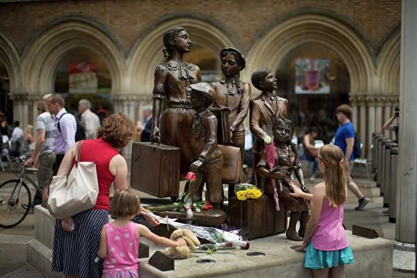 © AP Photo / Matt Dunham Люди кладут цветы к мемориалу "Киндертранспорт", расположенному на станции Ливерпуль-стрит в Лондоне