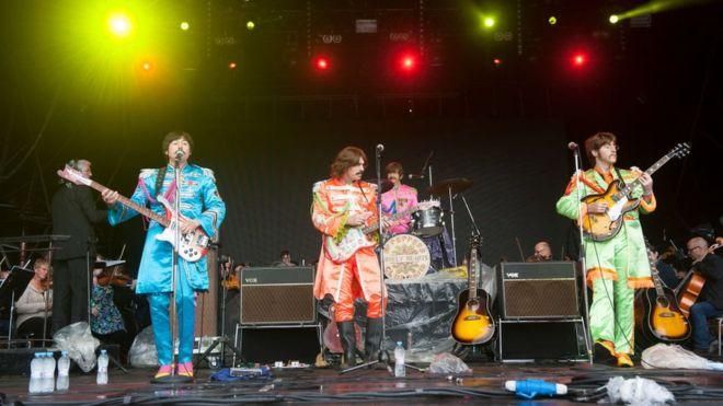 KATJA OGRIN Image caption Bootleg Beatles - самая знаменитая и самая успешная трибьют-группа в мире - во время выступления с Королевским филармоническим оркестром Ливерпуля на праздновании 50-летия альбома Sgt. Pepper's Lonely Hearts Club Band