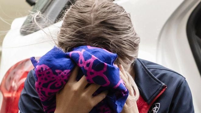 AFP Image caption Обвиняемая девушка перед входом в здание суда закрыла лицо платком
