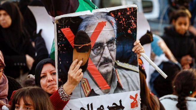 GETTY IMAGES Image caption Демонстрация в Триполи. На портрете Халифы Хафтара надпись "Нет военному преступнику!"