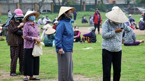 © REUTERS / Kham Женщины в защитных масках в очереди за бесплатным рисом в Ханое, Вьетнам