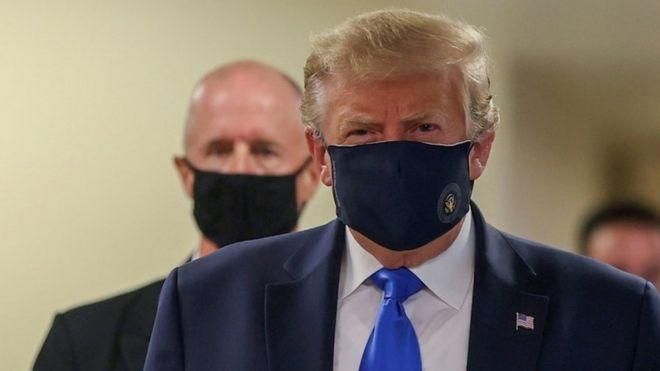 REUTERS Image caption Трамп в маске в коридоре во время начала визита в Национальный военно-медицинский центр имени Уолтера Рида