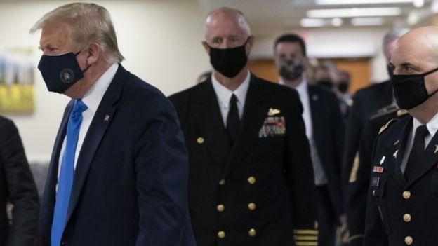 EPA Image caption Сбоку на черной маске Трампа - золотая президентская печать