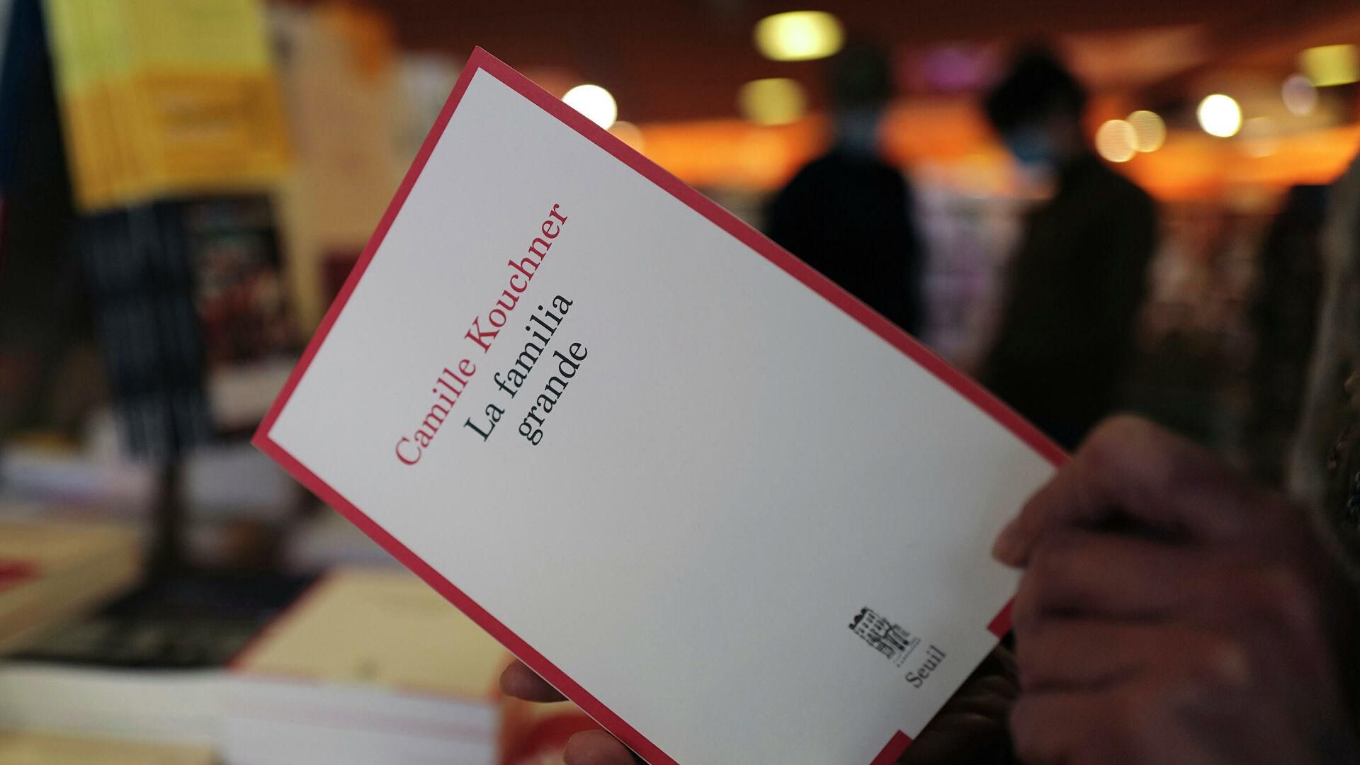 © AP Photo / Francois Mori Человек держит книгу Камиллы Кушнер "La Familia Grande" в книжном магазине Парижа