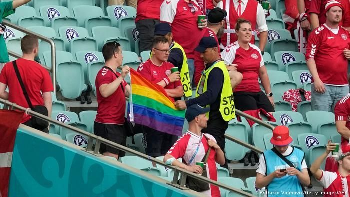 Стюарды и датский болельщик с радужным флагом на стадионе в Баку