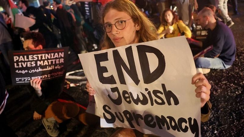 JACK GUEZ/AFP Подпись к фото, Сотни израильтян вышли в понедельник на акцию протеста в Тель-Авиве, призывая власти прекратить угнетение палестинцев и негодуя в связи с действиями еврейских погромщиков