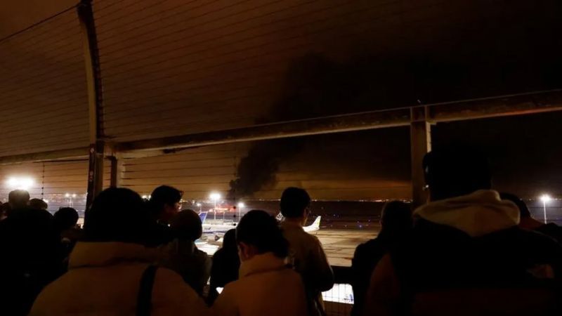 REUTERS Подпись к фото, Пассажиры наблюдают горящий самолет со смотровой площадки