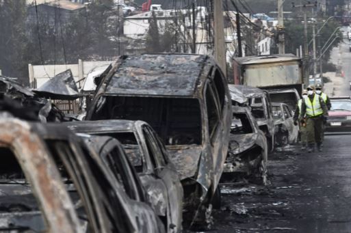 Чилийские «карабинеры» около сгоревших машин в результате лесного пожара в городе Кильпуэ, область Вальпараисо, 4 февраля 2024 г. AFP - RODRIGO ARANGUA